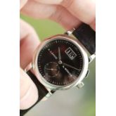 Saxonia 是 1994 年朗格复兴时推出的四款元祖表款之一，在品牌复兴方面发挥了核心作用。从借鉴自 Lange 1 的大日期到与 Tourbillon Pour le Mérite 相同的小钻石时标，早期 Saxonia 的设计抓住了时代精神。圆形表壳、内敛的尺寸和对称的表盘布局共同打造出一款适合当时品味的精致正装腕表。